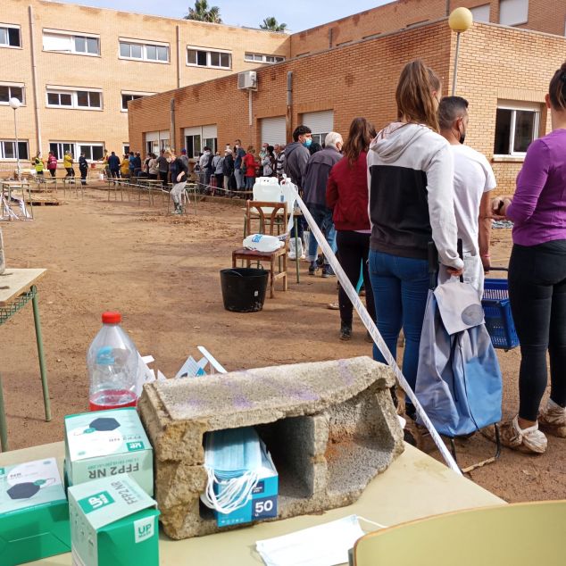 Persones fent cua a l'institut per recollir aliments i material